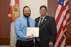 Two men holding certificate, U.S. and Florida flags