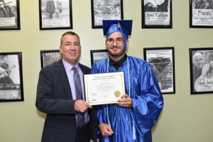 Graduate in blue cap and gown holding certificate