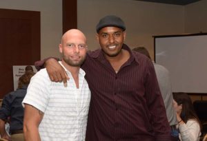 Two men smiling with arms around shoulders