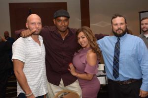 Four adults posing together at indoor event