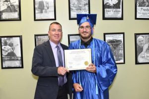 Graduate in blue cap and gown holding certificate