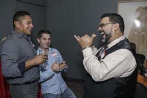 Three men laughing and drinking at party