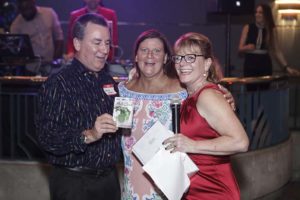 Three people smiling at party with microphone