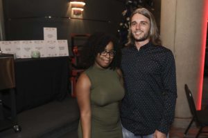 Two smiling people posing indoors at event