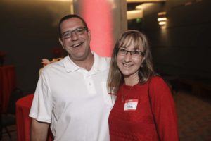Two smiling adults wearing glasses at event