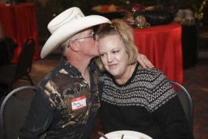 Man in cowboy hat kissing woman at party