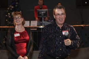 Man speaking into microphone beside smiling woman