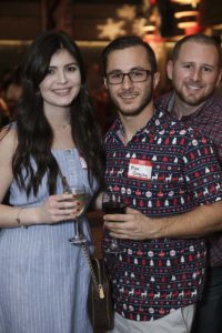 Three people holding drinks at party