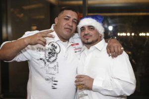 Two men smiling, one wearing Santa hat