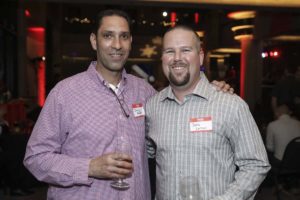 Two men smiling, holding wine glasses