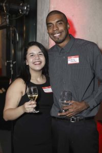 Two smiling people holding wine glasses at event