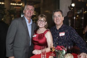 Three adults smiling, woman wearing red dress