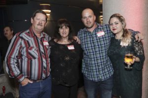 Four people smiling at a social event
