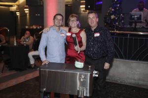 Three people smiling behind metal cooler