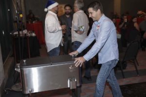 Man pushing metal cooler at holiday party