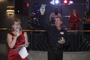 Charity auction: woman speaking, man holding item