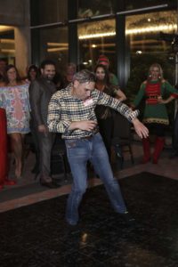 Man dancing at holiday party with onlookers