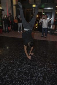 Breakdancer handstand on dance floor amid crowd