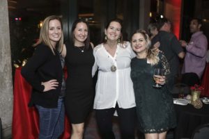 Four smiling women at indoor evening party