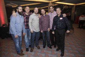 Six men posing together at indoor event