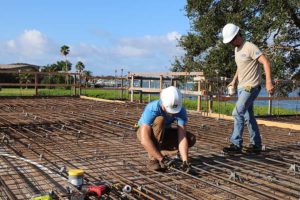 Construction workers securing rebar on waterfront slab
