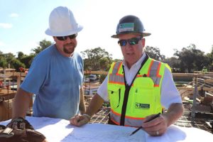 Two workers in hard hats reviewing blueprints