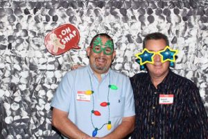 Two men wearing novelty glasses at photo booth