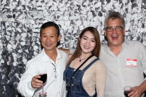 Three smiling adults holding wine glasses