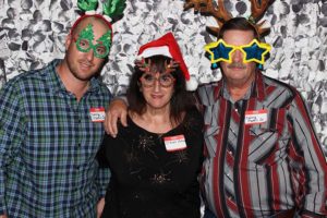 Three people wearing Christmas hats and novelty glasses