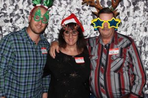 Three people wearing festive holiday props posing