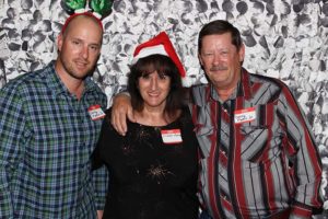 Three adults wearing holiday hats and name tags