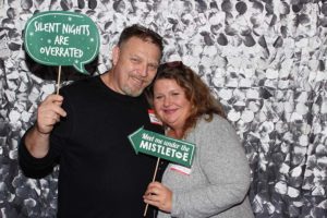 Smiling couple holding holiday photo booth signs