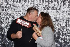 Couple kissing while holding holiday photo booth signs