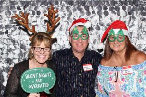 Three people wearing Christmas hats and props