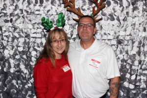 Smiling couple wearing reindeer antlers, holiday backdrop
