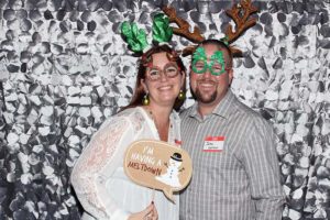 Smiling couple in reindeer antlers and festive glasses