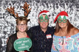 Three adults wearing Christmas hats and glasses