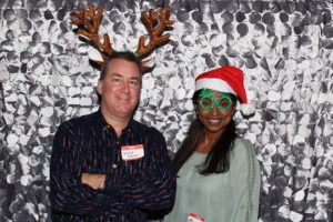 Two people in holiday hats and green glasses