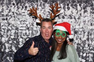 Smiling pair wearing reindeer antlers and Santa hat