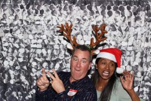 Two people wearing reindeer antlers and Santa hat
