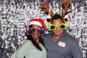Two people wearing oversized holiday glasses and antlers