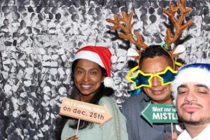 Three people posing with Christmas photo booth props