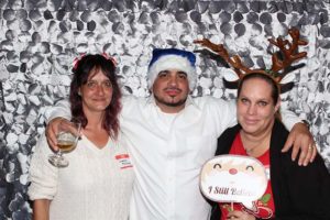 Three adults in festive hats at photo booth