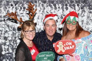 Three adults wearing Christmas hats and props