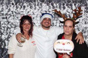 Three people in Christmas hats holding sign