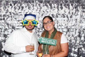 Two people with mistletoe sign and star glasses