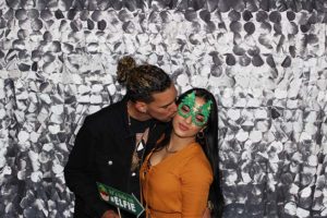 Man kissing woman wearing green glitter mask