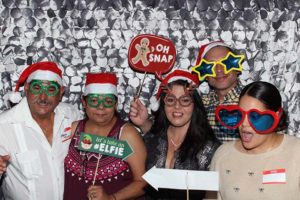 Five people wearing Santa hats and novelty glasses