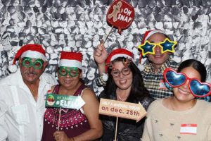 Five people wearing Santa hats and novelty glasses