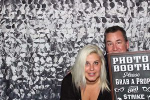 Two people posing in photo booth with sign